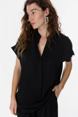 Blusa negra con escote en V, mangas cortas y detalles desflecados en las mangas y el bajo.