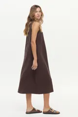 Vestido midi de corte recto y color marrón camel, con cuello redondo, sin mangas y costuras pespuntadas visibles con diseño geométrico en el frente.