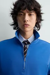 Sudadera de algodón azul con cuello alto y cierre frontal de cremallera de un cuarto. Presenta un corte regular y puños y bajo en rib.