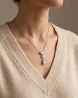 Collar de acero con colgante de tres circonias: una ovalada en la parte superior, una pequeña redonda en el centro y una circonia en forma de lágrima en la base.