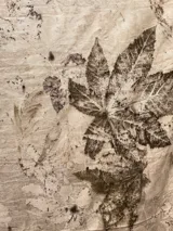 Mantel rectangular de lino y algodón en dos tonos, con estampado artesanal de hojas y flores.