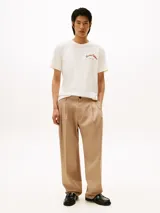 Remera de cuello redondo y manga corta, confeccionada en algodón regenerativo. Presenta un diseño minimalista en color blanco con el logo de la marca bordado en el pecho en tonos cálidos.