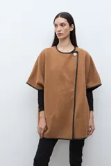 Capa color tostado con vivos en contraste de color negro, cierre frontal con un botón grande y un bolsillo lateral.