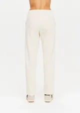 Pantalón deportivo color crema de corte recto con cintura elástica, cordón de ajuste y cinta de rayas plateadas en los laterales.