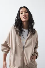 Campera con capucha y cierre frontal, de silueta relajada, hombros caídos y bolsillos laterales. Presenta terminaciones elastizadas en puños y ruedo, con líneas de recorte frontales y cierre metálico con tirador circular.