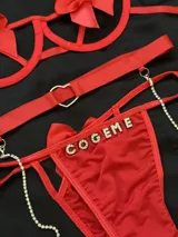 Conjunto de lencería rojo compuesto por soutienne con aros y moños decorativos, bombacha vedetina con letras de strass y tiras regulables, y portaligas con arnés y cadenas de brillantes.