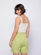 Bermuda de algodón color verde lima, de corte recto y tiro alto. Presenta cierre frontal con botones veteados, bolsillos laterales y elástico en la pretina trasera para mayor ajuste.