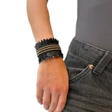 Pulsera tipo brazalete hecho en lentejuelas negras y strass dorados, con base metálica ajustable.
