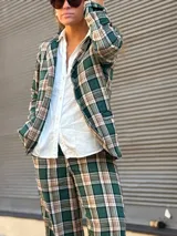 Blazer de corte recto con estampado de cuadros en tonos verdes, beige y negro, con cierre frontal de botones y bolsillos laterales.