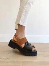 Sandalias de cuero color negro y camel, con plataforma track y hebilla ajustable.