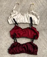 Pack de tres tops de breteles finos y volados en el escote, uno color crema y dos color borgoña.