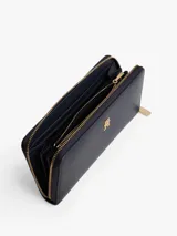 Billetera rectangular de color azul marino con acabado liso y cierre perimetral de cremallera dorada. Presenta una insignia metálica con el monograma TH en el frente.