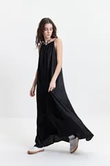 Vestido largo de silueta amplia y fluida, con breteles finos y escote redondeado. Presenta un diseño estampado con motivos geométricos en tonos bordó, beige y gris.