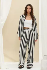 Pantalón de rayas verticales en blanco y negro, de corte ancho, con cintura elástica ajustable mediante cordón blanco.