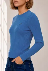 Sweater tejido de punto color celeste, con diseño de ochos verticales, cuello redondo y manga larga. Presenta detalles de bordado pequeño en el pecho.