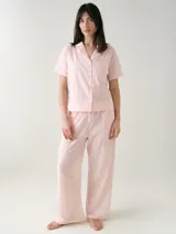 Camisa de manga corta para dormir confeccionada en broderie de algodón, con cuello solapa y cierre frontal con botones. Presenta un bolsillo aplicado en el pecho.