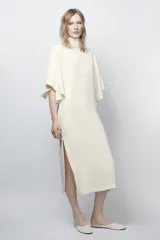 Vestido midi fluido de cuello alto y manga corta tipo capa. Presenta un diseño minimalista con bajo recto y aberturas laterales, con cierre en la espalda.