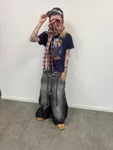 Bufanda larga con diseño de cuadrille en tonos rojo, marrón, negro y blanco. Presenta terminaciones con flecos en los extremos, una grifa de goma con logo en una punta y una etiqueta tejida con logo en la otra.