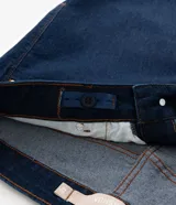 Pantalón skinny de jean en color azul marino, de tiro alto y corte ajustado. Presenta bolsillos delanteros y traseros, trabillas en la cintura y cierre de botón y cremallera.