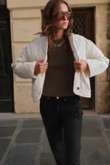 Chaqueta acolchada de cuello redondo y manga larga, con cierre frontal de botones y dos bolsillos delanteros de plastrón. Presenta un diseño de costuras en forma de rombos.