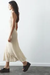 Vestido midi de encaje color crudo, con escote recto y hombros descubiertos. Detalle de tira con lazo combinada a tono. Forro interior y cierre lateral con cremallera oculta en costura.