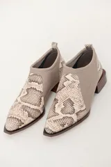 Botín color visón con estampado de reptil, confeccionado en cuero vacuno y neopreno. Tiene punta fina y taco cuadrado con puntas redondeadas.