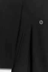 Blazer negro de corte entallado con cuello solapa, manga larga y cierre frontal cruzado con dos botones.