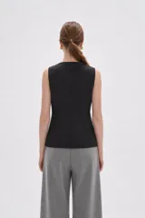 Chaleco sin mangas de corte sastrero, color marrón con diseño de rayas verticales finas. Presenta cuello redondo, cierre frontal con botones y dos bolsillos laterales simulados.