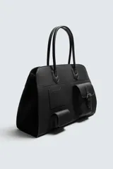 Bolso de viaje negro con acabado grabado y diseño de múltiples bolsillos frontales. Dispone de un compartimento principal con cierre magnético, un bolsillo interno con cremallera y tres bolsillos exteriores de diversos tamaños con cierre de imán. Incluye dos asas de mano superiores.
