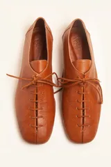 Zapato tipo oxford plano de cuero vacuno en color azul marino, con cordones al tono y suela de cuero.