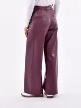 Pantalón de corte ancho y relajado, confeccionado en cuero sintético color borravino. Cuenta con bolsillos frontales aplicados de diseño geométrico, tiro alto y trabillas para cinturón.