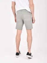 Bermuda de gabardina color oliva, con diseño de cinco bolsillos, cierre frontal con botón y detalles de desgaste sutiles.