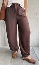 Pantalón de corte babucha color chocolate, de diseño holgado con cintura elástica fruncida y cordón ajustable.