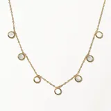 Collar dorado con cadena fina y dijes circulares de nácar.