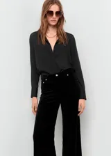 Pantalón de terciopelo negro de tiro medio y diseño wide leg con cinco bolsillos, cierre de botón y cremallera, y trabillas para cinturón.