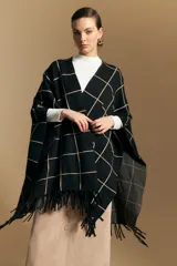 Poncho abierto de tejido de punto con diseño de cuadros grandes en contraste. Presenta un patrón reversible en tonos negro y marrón, con un estilo envolvente y versátil.