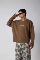 Sweater de cuello redondo en color marrón moka, con diseño de tejido acanalado y calce holgado. Presenta una estampa pequeña en el centro del pecho.