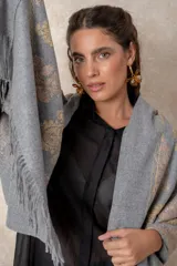Pashmina de tela densa y suave, con caída pesada y diseño bordado con motivos florales en tonos dorados y beige. Presenta terminaciones con flecos en los extremos.