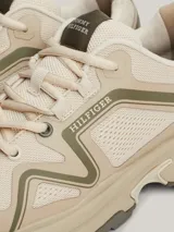 Zapatillas de running Tommy Hilfiger color beige con detalles en verde oliva. Capellada de tejido de punto y paneles de malla, suela dentada de goma y caucho, logo de Tommy Hilfiger Sport en el lateral y detalle distintivo en el talón.