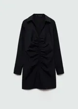 Vestido corto de estilo camisero, color negro con estampado de rayas verticales finas. Presenta cierre frontal con cremallera, detalle de fruncido central, cuello camisero y mangas largas con puños abotonados.