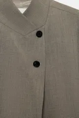 Blazer de cuello subido con cierre frontal cruzado de botones. Presenta manga larga con hombreras y puños con botones, bolsillos de vivo en el delantero y forro interior.