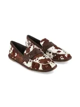 Mocasín de cuero con pelo vacuno en tonos marrón y blanco, con diseño clásico de antifaz y detalles fruncidos.