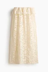 Pollera midi de encaje color beige, de corte holgado con cintura elástica y volado ancho en la parte superior.