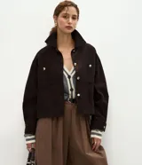 Campera Marfinno de pana marrón oscuro, con cuello clásico, cierre frontal de botones metálicos dorados, bolsillos frontales con solapa y manga larga con puños abotonados.