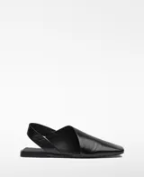 Zapato plano destalonado de piel negra con diseño asimétrico y puntera cuadrada. Cuenta con tira elástica en el talón y plantilla Memory Foam.