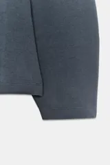 Jersey de cuello redondo y manga larga, confeccionado en tejido de punto elástico con trama compacta. Presenta un diseño con pinzas en la cintura que le otorgan una silueta entallada.
