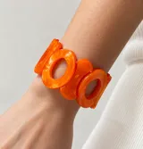 Pulsera elástica de resina color naranja, compuesta por piezas geométricas ovaladas unidas entre sí.