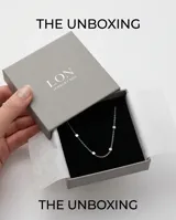 Collar de cadena fina de acero con pequeños dijes en forma de cubo distribuidos a lo largo de la pieza.