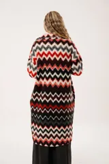 Tapado largo de lana con estampado de zigzag horizontal en tonos rojo, negro, blanco y gris. Presenta cuello camisero, cierre frontal con botones y bolsillos laterales.