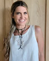 Collar de estilo choker con tiento de cuero negro, que presenta un dije grande en forma de estrella de metal plateado y detalles de cuentas de colores.